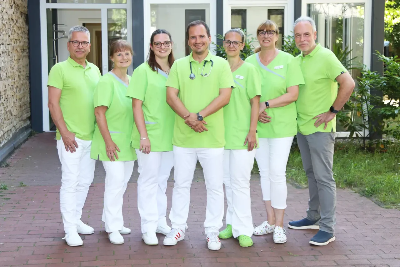 Gruppenfoto des Teams der Hausarzt-Praxis vor dem Praxisgebäude (3 Ärzte und 4 Mitarbeiterinnen)