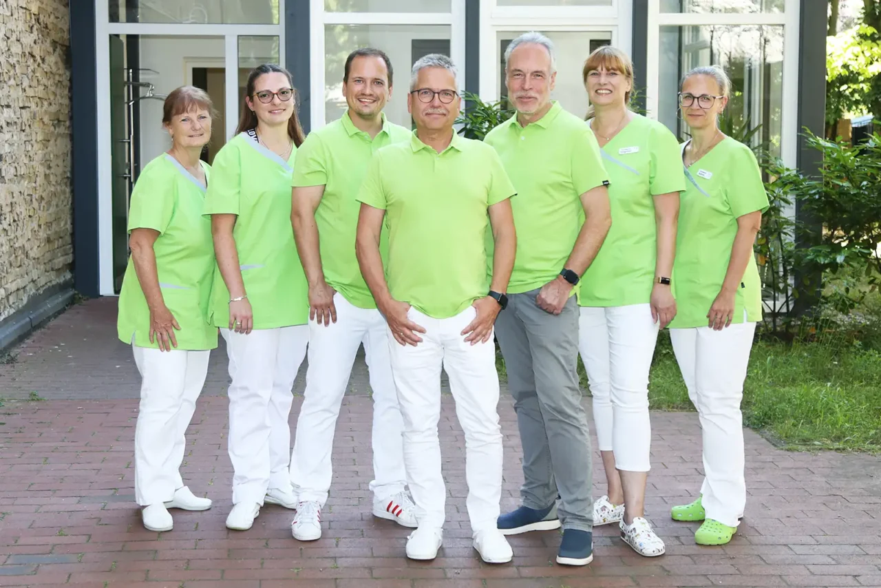 Gruppenfoto des Teams der Hausarzt-Praxis vor dem Praxisgebäude (3 Ärzte und 4 Mitarbeiterinnen)